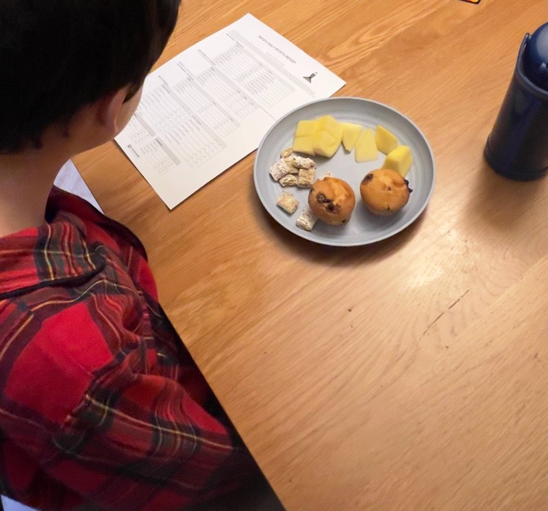 Kid reading a printed sports report at the breakfast table